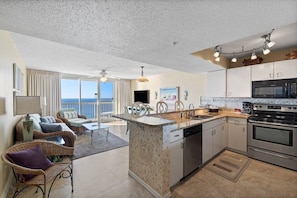 Relax in a spacious living area with a sofa and chairs, kitchenette, and dining table, offering a view of the ocean.