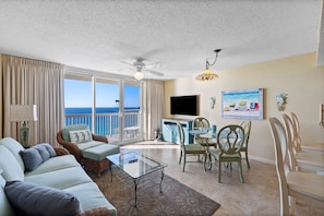 Enjoy ocean views from the balcony, featuring a spacious living area with a sofa, armchairs, and dining table.