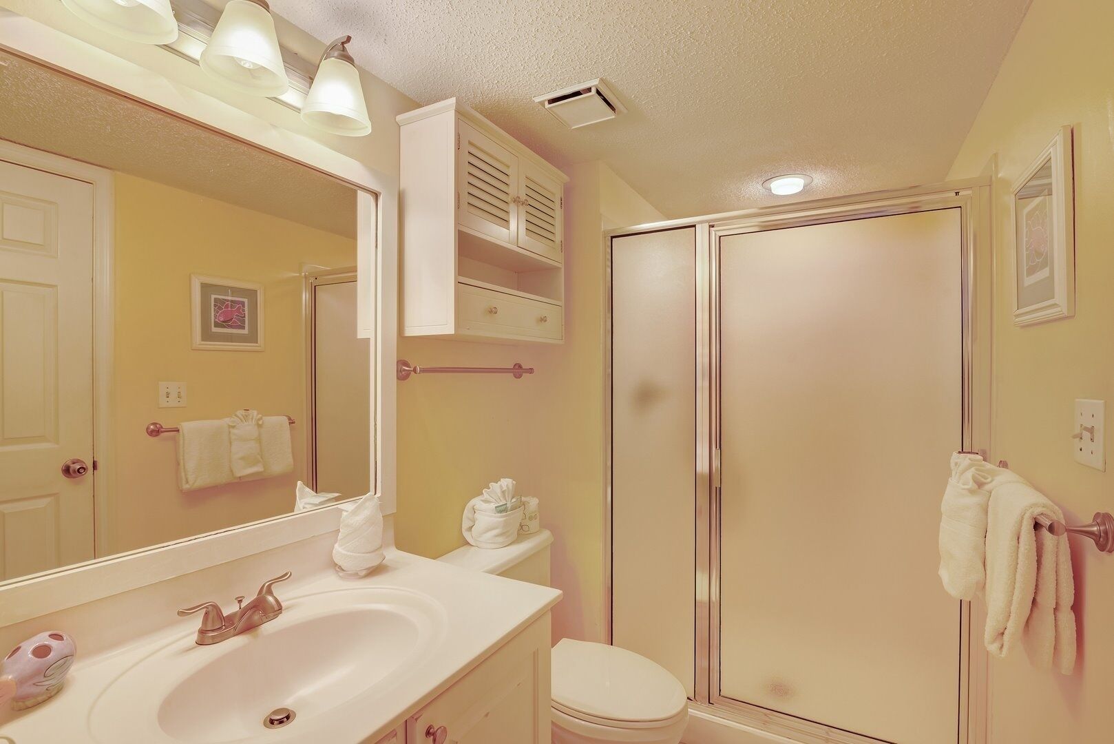 A bathroom with a sink, mirror, toilet, and shower.