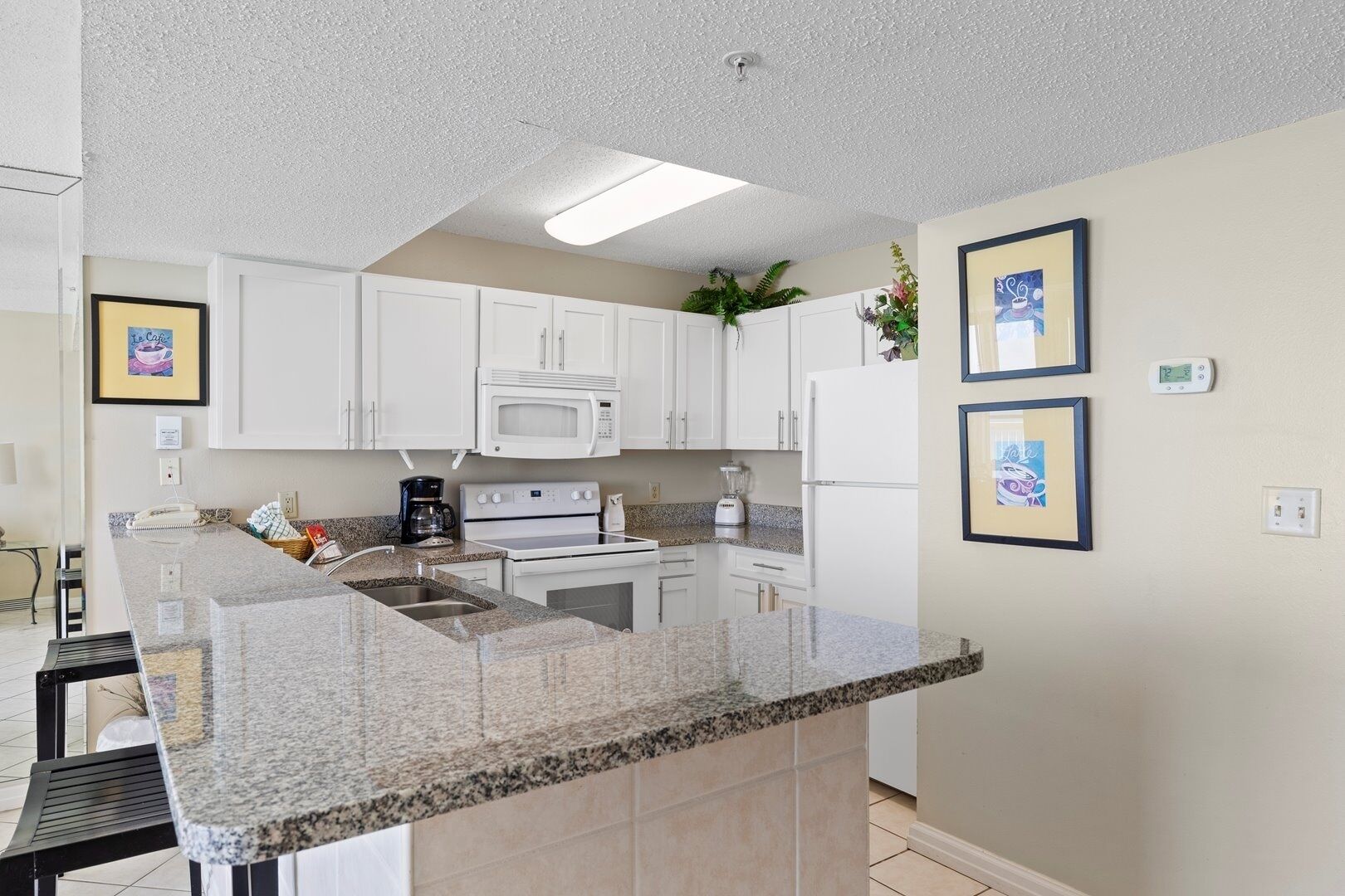 A modern kitchen with white cabinets, a granite countertop, and a built-in oven.
