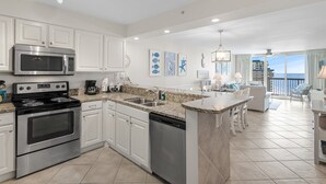 A modern kitchen with white cabinetry, stainless steel appliances, and a granite countertop. - Pelican Beach 1716 2 Bedroom Condo by Pelican Beach Management (Destin)