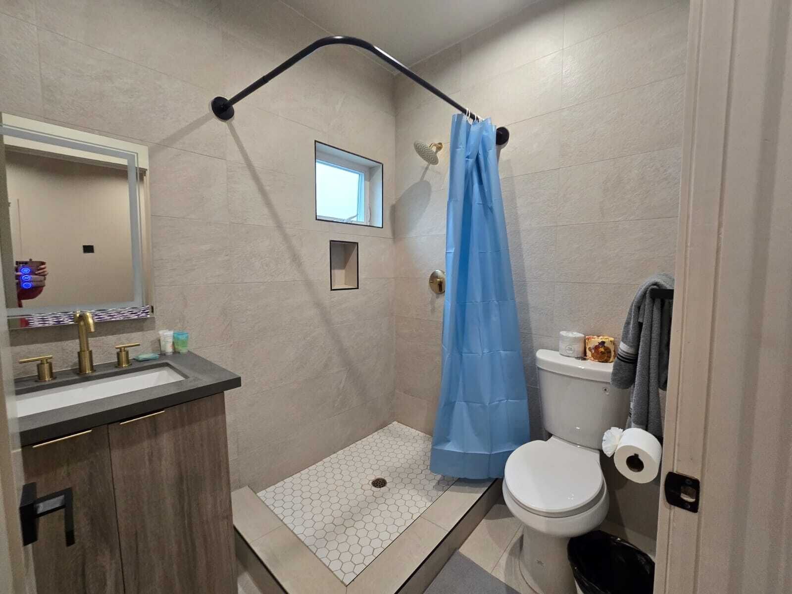 A modern bathroom with a shower, toilet, and sink.