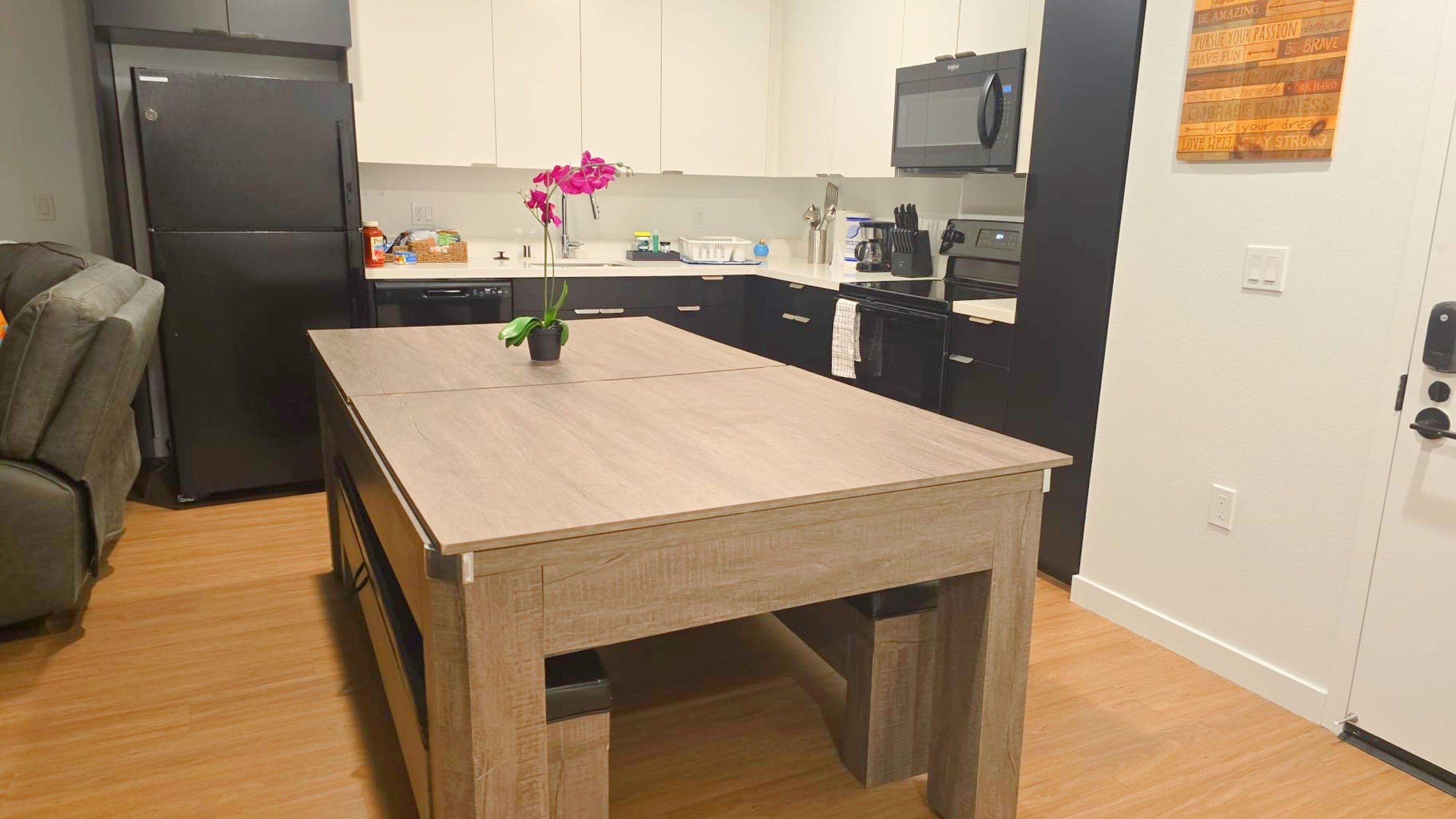 A compact kitchen with a central island, a refrigerator, microwave, and oven.