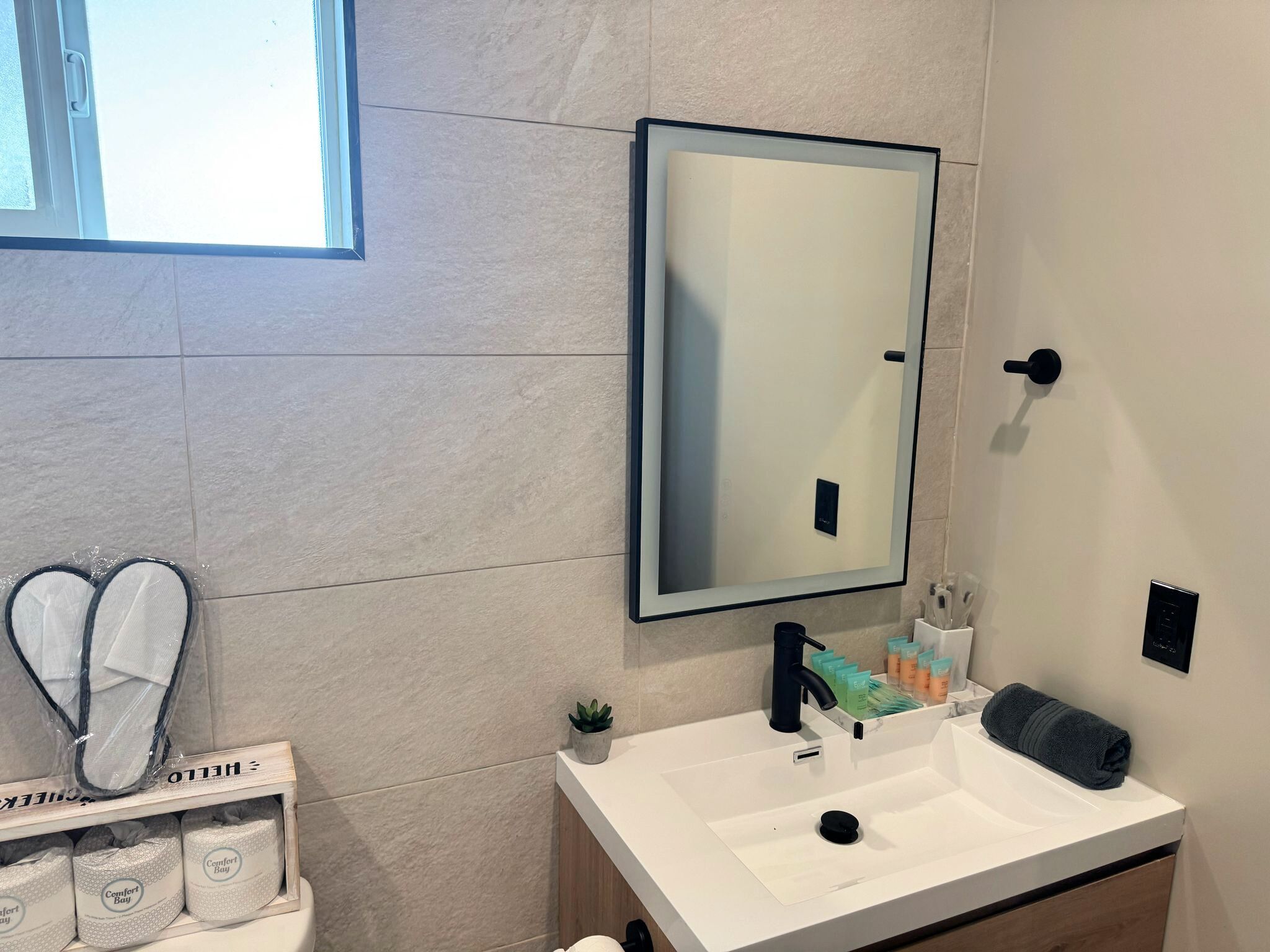 A bathroom with a white sink, a mirror, and a shelf with toiletries.