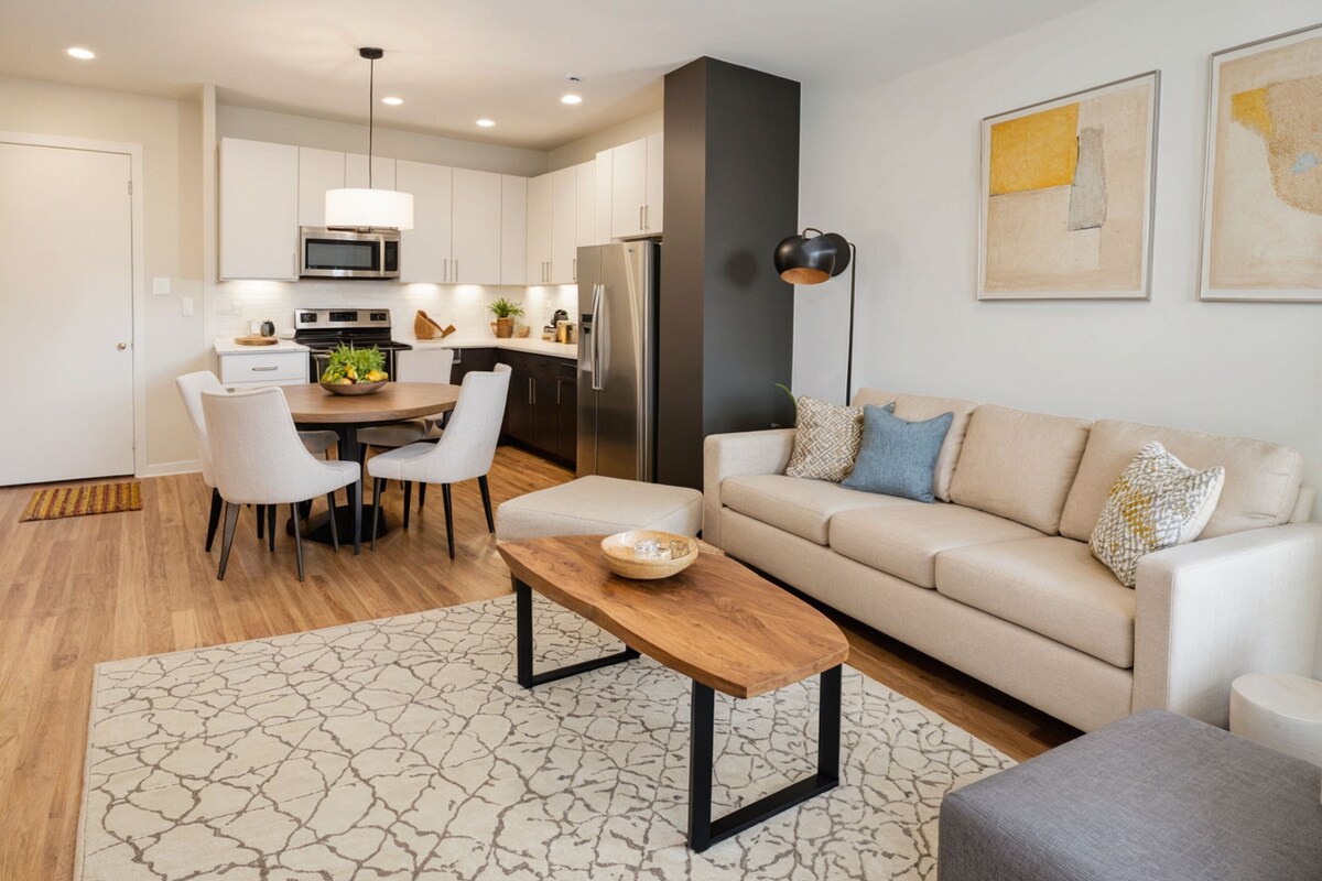 A modern living room with a sofa, a coffee table, and a dining area with chairs and a table.
