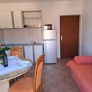 Et kompakt køkken med et køleskab, mikroovn og en lille spiseplads med bord og stole.