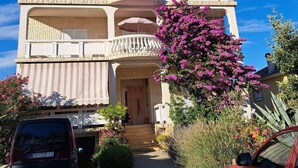 A two-story building with a balcony, a driveway, and parked cars. - Apartments Mirjana (Vrsi)