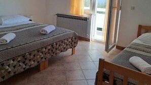 A hotel room with two beds, a radiator, and a view of the outside. - Apartments Mirjana (Vrsi)