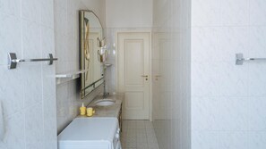 A bathroom with a white sink, mirror, and door.