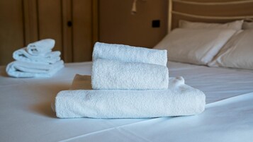 Una cama bien hecha con una pila de toallas blancas dobladas a un lado.