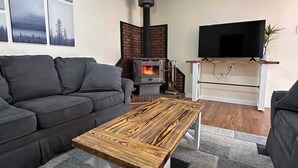 Ein modernes Wohnzimmer mit Kamin, Sofa, Couchtisch und Fernseher.