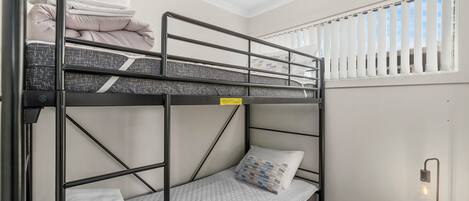 Habitación con literas, una mesita de noche y una lámpara.