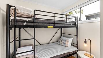 A bunk bed with a mattress, pillows, and folded blankets.