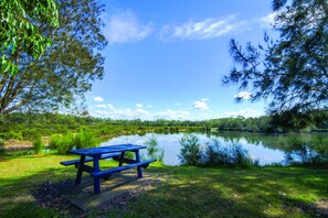 A picnic table by a calm lake surrounded by lush greenery.