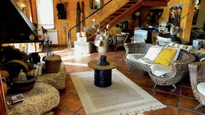 A cozy living room with wicker furniture, a stone coffee table, and a rustic staircase.