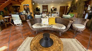 A cozy living room with a wicker sofa, a coffee table, and a rustic stone wall.