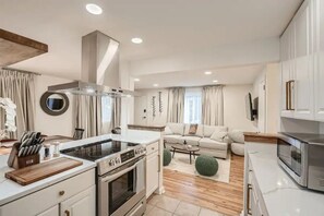A modern kitchen with a central island, built-in oven, and stainless steel appliances. - Modern Buckhead Duplex 2Br 2Ba - Walk Everywhere! Pet-Friendly (Atlanta)