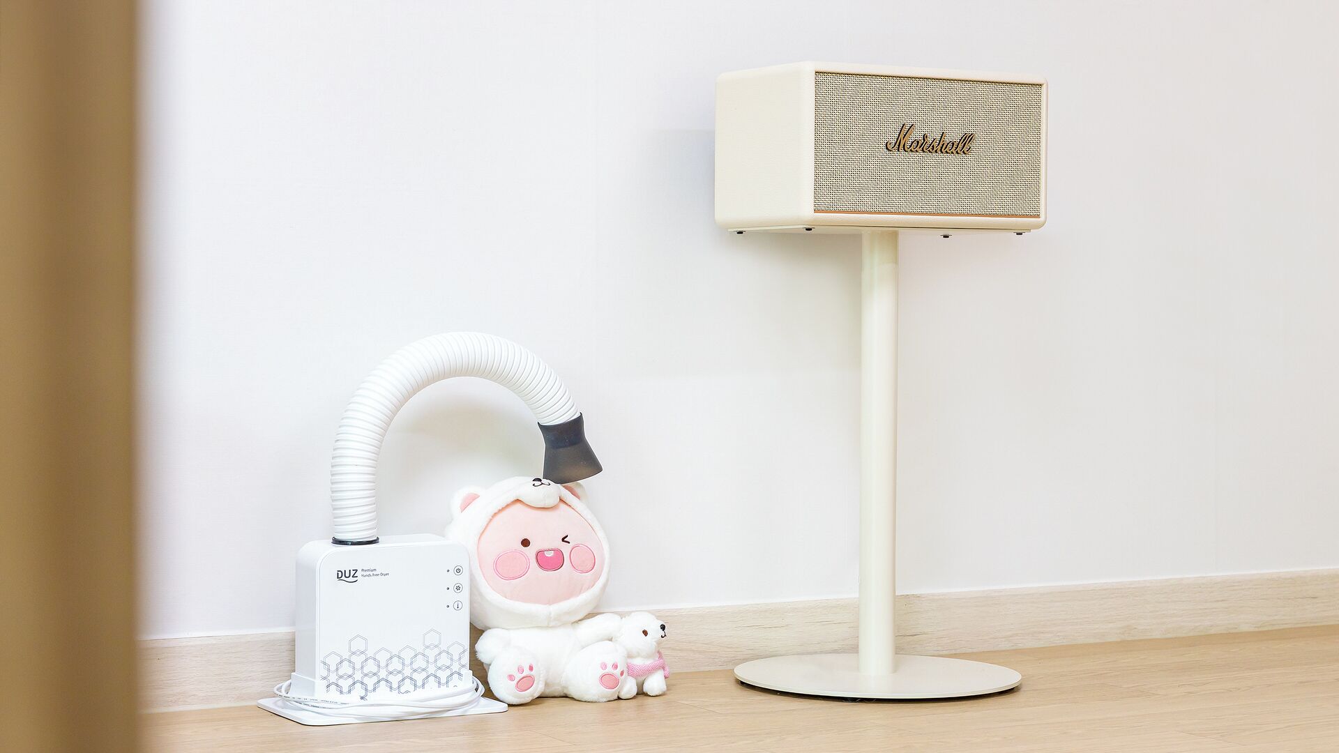 A white portable heater, a plush toy, and a white stand-alone fan.
