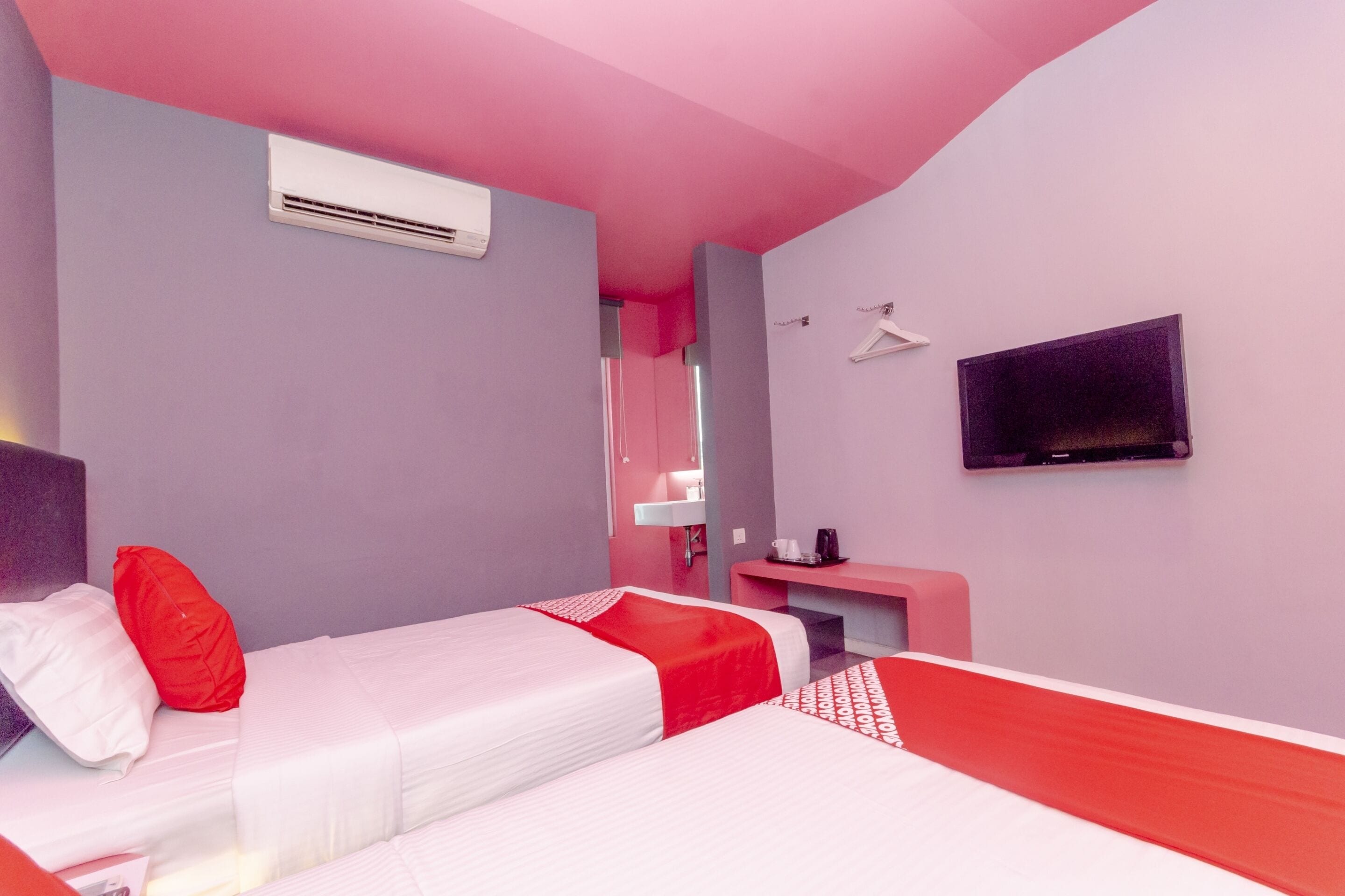 A hotel room with two beds, a TV, a desk, and a mirror.