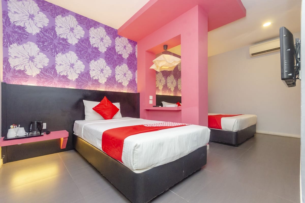 Une chambre d’hôtel moderne, dotée d’un grand lit, d’une table de chevet, d’un miroir et d’un téléviseur fixé au mur.