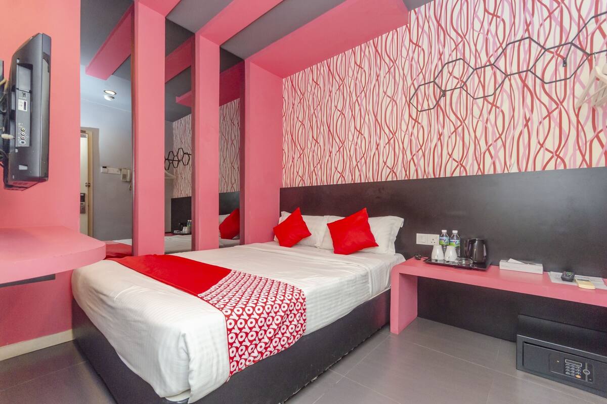 Une chambre d’hôtel moderne équipée d’un lit, d’une table de chevet et d’un téléviseur fixé au mur.
