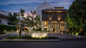 A modern hotel with a prominent entrance, a landscaped garden, and a clear sky at dusk. - Maladee Rendezvous Hotel Chiang Mai (Chiang Mai)