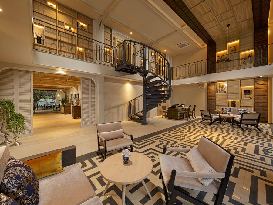 A spacious lobby with a central staircase, seating areas, and a dining space.
