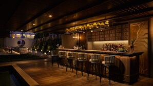 A bar area with wooden flooring, bar stools, and a shelf with bottles. - Maladee Rendezvous Hotel Chiang Mai (Chiang Mai)