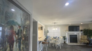 Un ampio soggiorno con camino, un'area pranzo con lampadario e un grande quadro astratto.