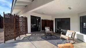 Una veranda esterna con un divisorio in legno, una poltrona a dondolo, un divano e uno sgabello di legno.