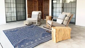 Un soggiorno moderno con un tappeto azzurro a motivi decorativi, due poltrone a dondolo e un tavolino in legno.