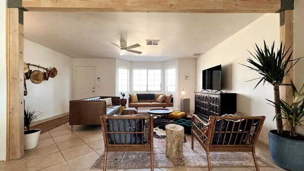 Un accogliente soggiorno con un divano marrone, due poltrone in vimini, un tavolino da caffè e una TV su un mobile in legno.