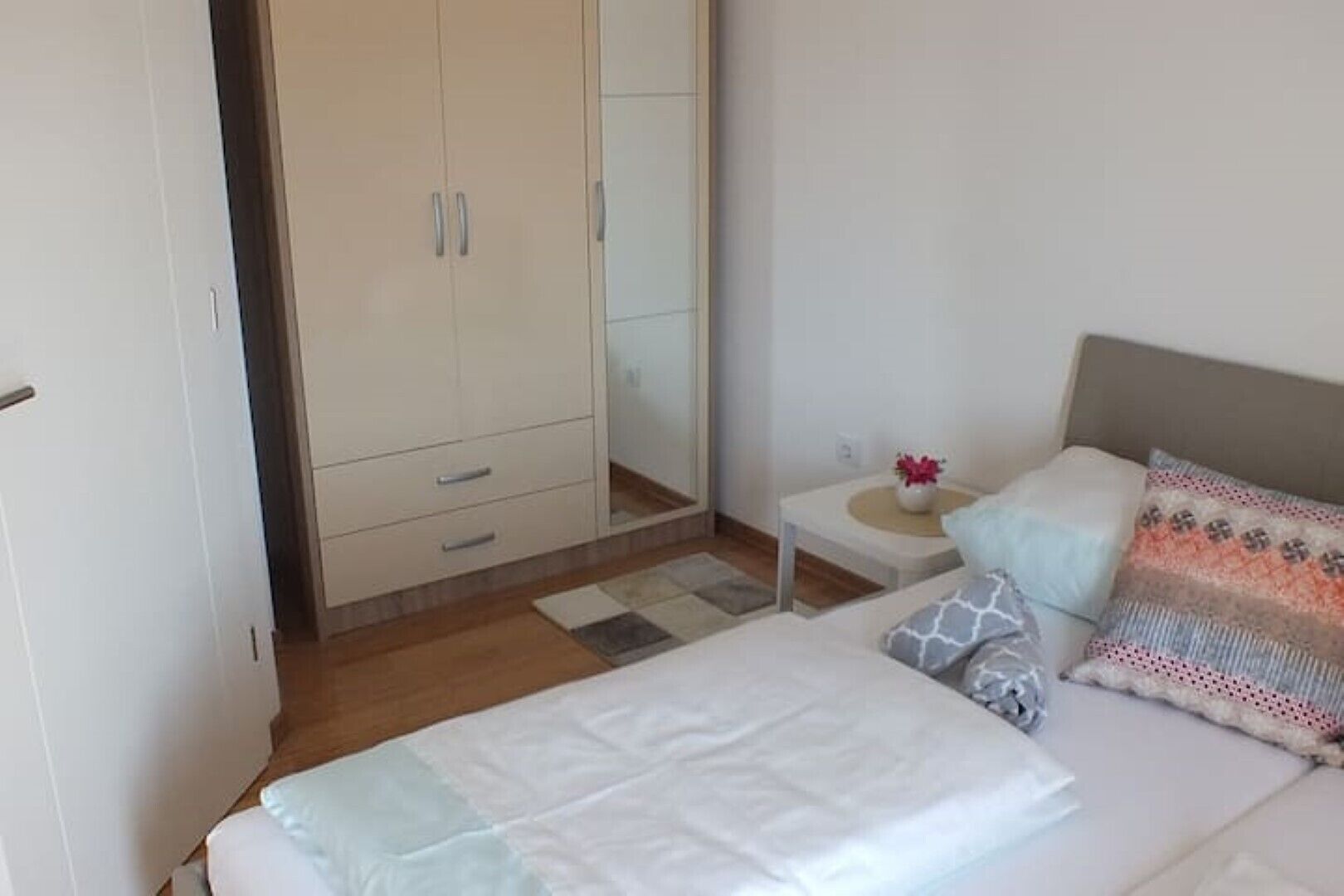 Une chambre à coucher comprenant un lit, une table de chevet, une commode, une armoire et un miroir.