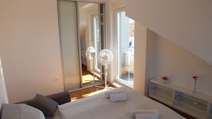 Ein Schlafzimmer mit Bett, Nachttisch, Spiegel und Fenster.
