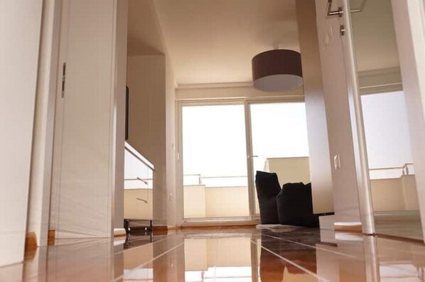 A spacious room with a large window, a black chair, and a ceiling light. - Ferienwohnung "calimero" - mit Meerblick (Novalja)