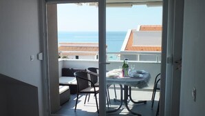 Ein Balkon mit Esstisch, einer Sitzecke und Blick auf das Meer und die Gebäude.