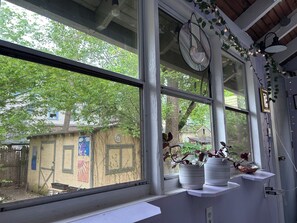 A room with large windows, a clock, and potted plants on the windowsill.