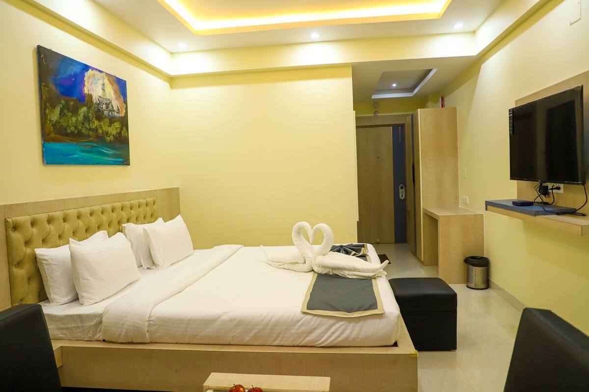 Une chambre d’hôtel avec un lit, un tableau au mur, une télévision et un bureau.