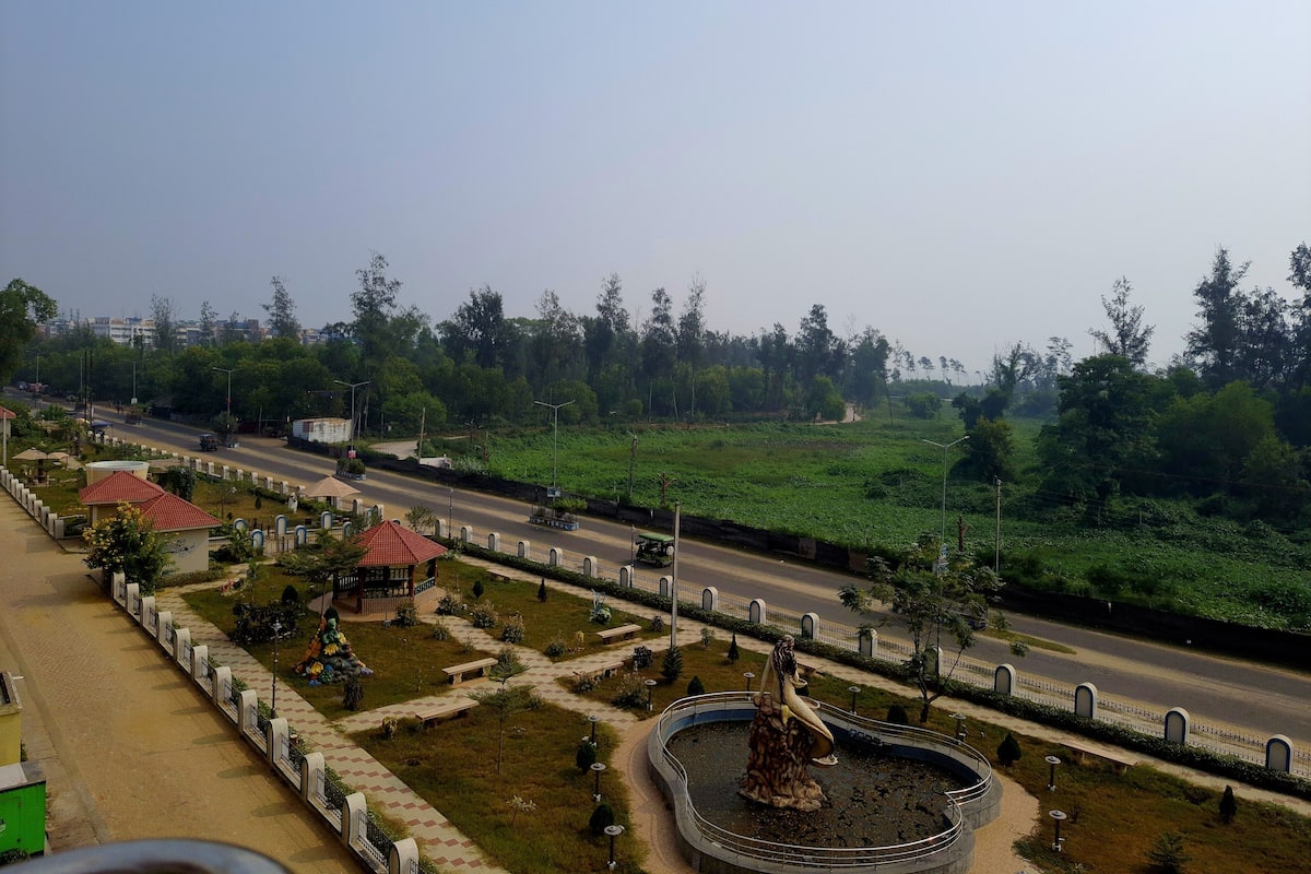 Un parc avec une fontaine, des bancs et une route.