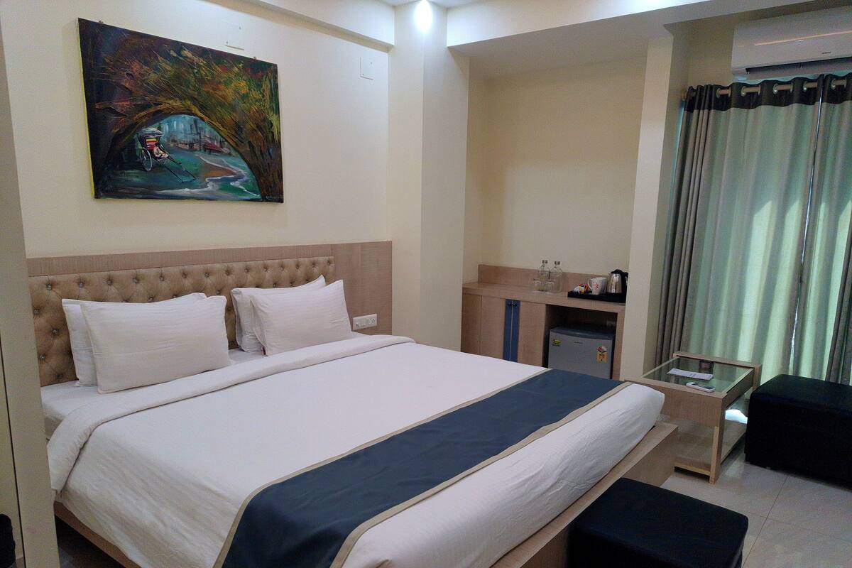 Une chambre d’hôtel avec un grand lit, une table de chevet, un bureau et un tableau au mur.