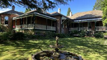 Traditional brick house with a charming front porch and serene garden featuring a central fountain.