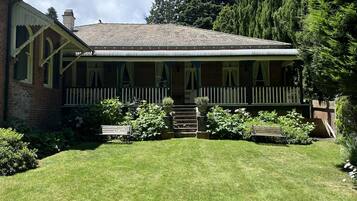 A two-story house with a porch, brick walls, and a well-maintained lawn.