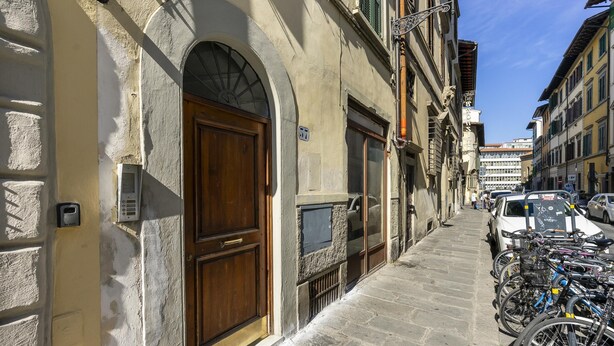 A narrow cobblestone street lined with historic buildings, a row of parked bicycles, and a white car. - Ruote for Three in Firenze (Florence)