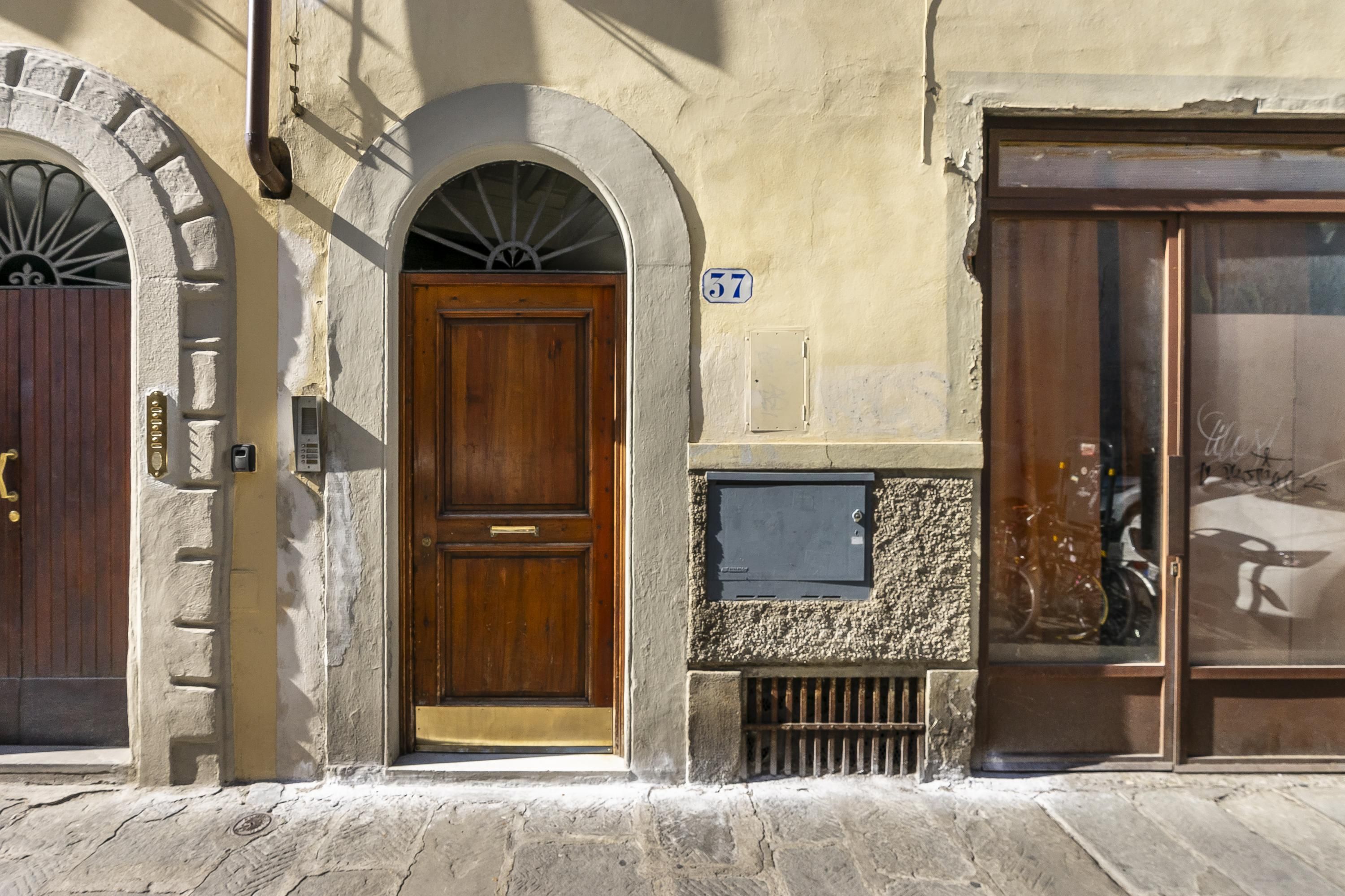 A building with a wooden door, a stone wall, and a window with a bicycle inside.