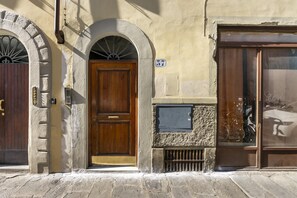 A building with a wooden door, a stone wall, and a window with a bicycle inside.