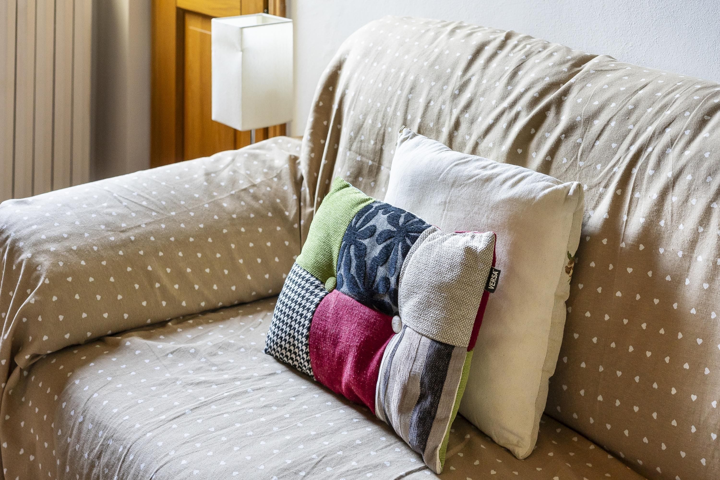 A sofa with a patterned fabric and multiple pillows, including a decorative one.