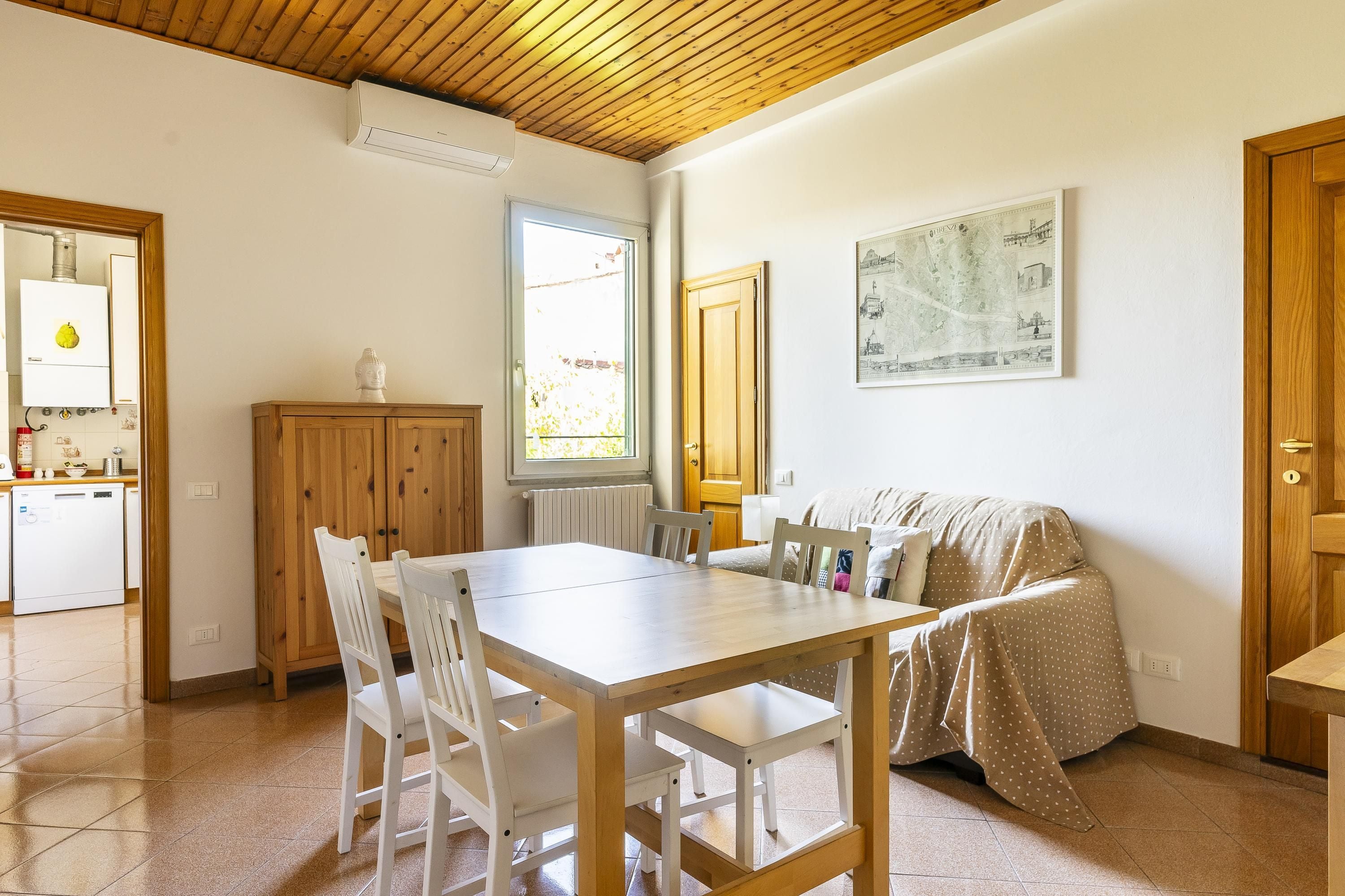 A dining area with a wooden table and chairs, a sofa, and a radiator.
