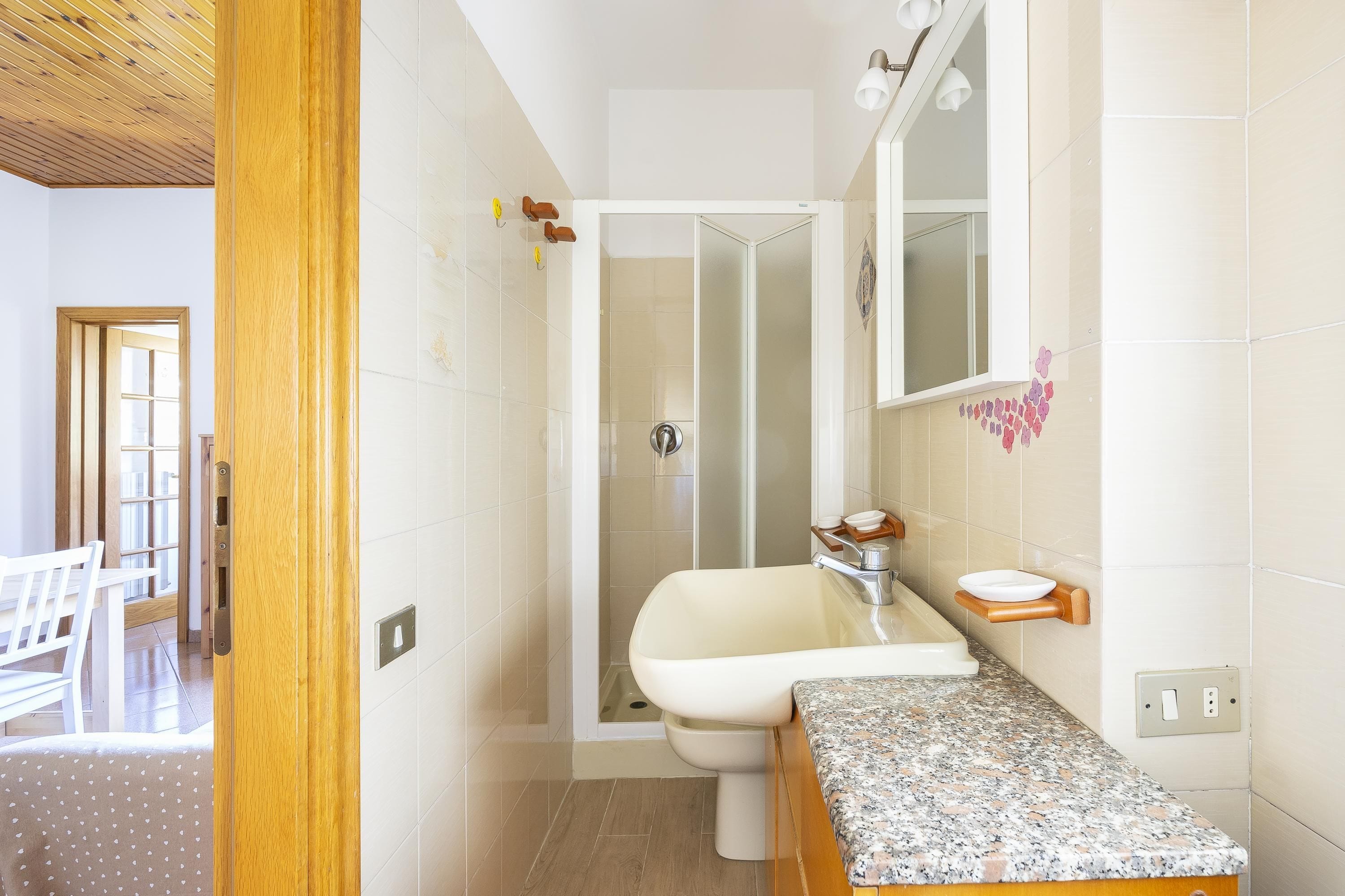 Baño con ducha, lavamanos y espejo.