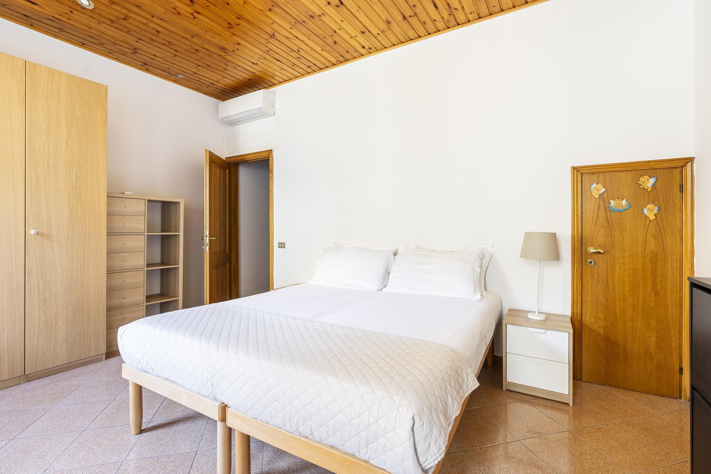A bedroom with a wooden bed, a nightstand, a wardrobe, and a door with angel decorations.