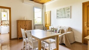 A dining area with a wooden table and chairs, a sofa, and a radiator. - Ruote for Three in Firenze (Florence)